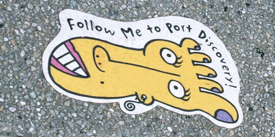 A sidewalk graphic film has a cartoon foot with a face and the words 