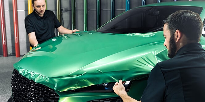 Installers applying 3m protective car wrap film
