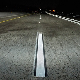 Roadway at night with white reflective centerline markings.