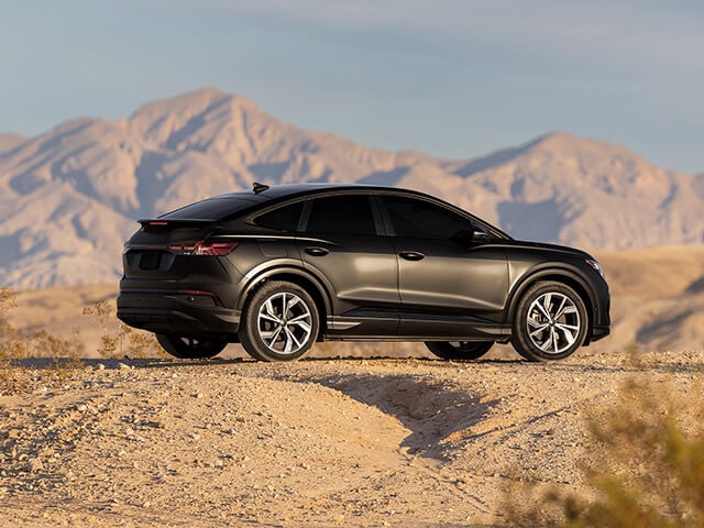 Black sedan with matte paint protection parked offroad with mountains in the background