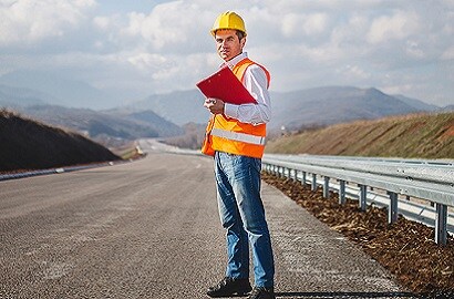 Road maintenance worker standing on an unmarked road.