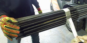 A man holding steal bars being bundled together using tape
