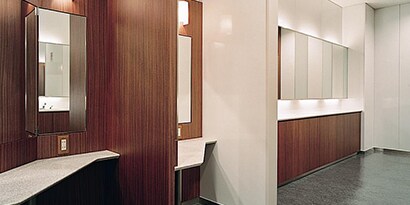 The sleek interior of a building has wood-grain walls and cream-colored features.
