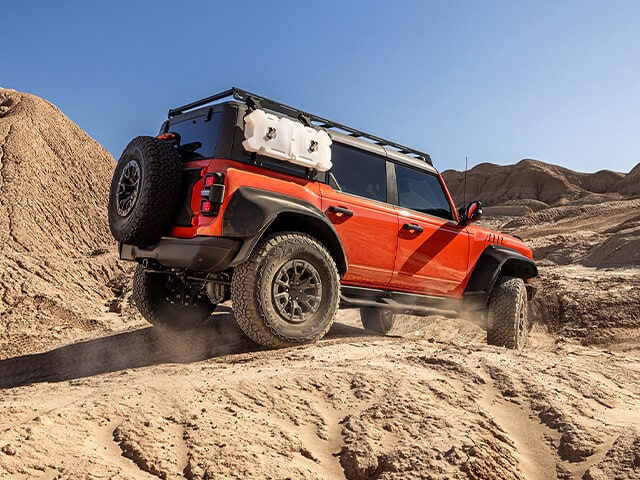 SUV with habanero red protection wrap film driving offroad in the desert