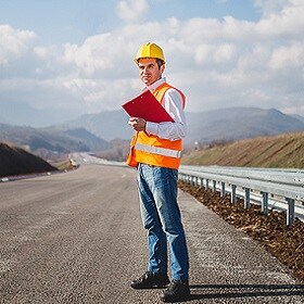 Road maintenance worker standing on an unmarked road.