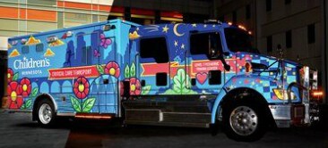 A food delivery van has a blue and white vehicle wrap displaying images of food.
