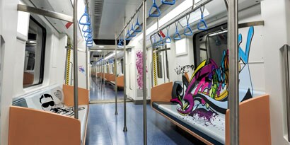 The interior of a subway car is marked with graffiti.
