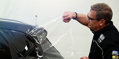 person putting a plastic wrap on a car
