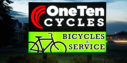 An illuminated sign for a bicycle shop is bright and colorful.
