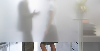 Behind an interior window covered with 3MTM Glass Finishes, we see the blurred shapes of a man and woman having a conversation.

