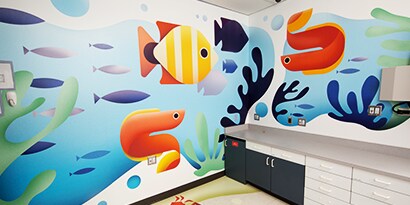 A wall has a graphic wrap with images of cheerful, brightly colored fish.
