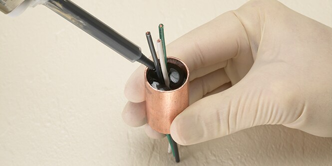 Encapsulating electrical chords with bonding adhesives by hand.
