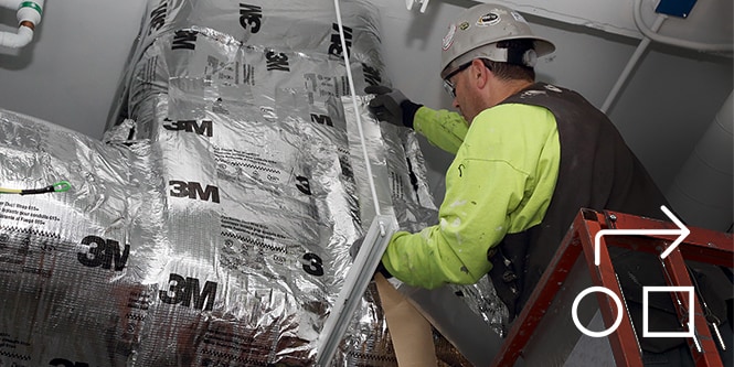 Image of a contractor installing a 3M fire barrier around ductwork
