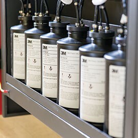 a row of ink bottles for digital printers on a shelf.