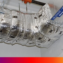 Image of ductwork labeled “Lab Exhaust” and wrapped in a 3M fire barrier