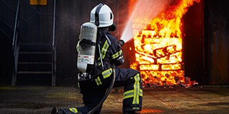 firefighter walking toward a burning house

